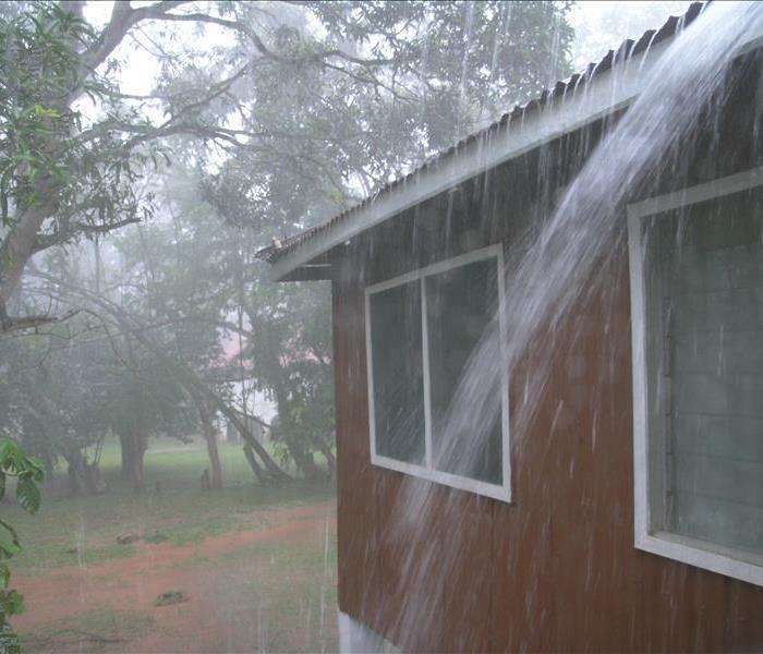 rain pouring down off the roof of a house 